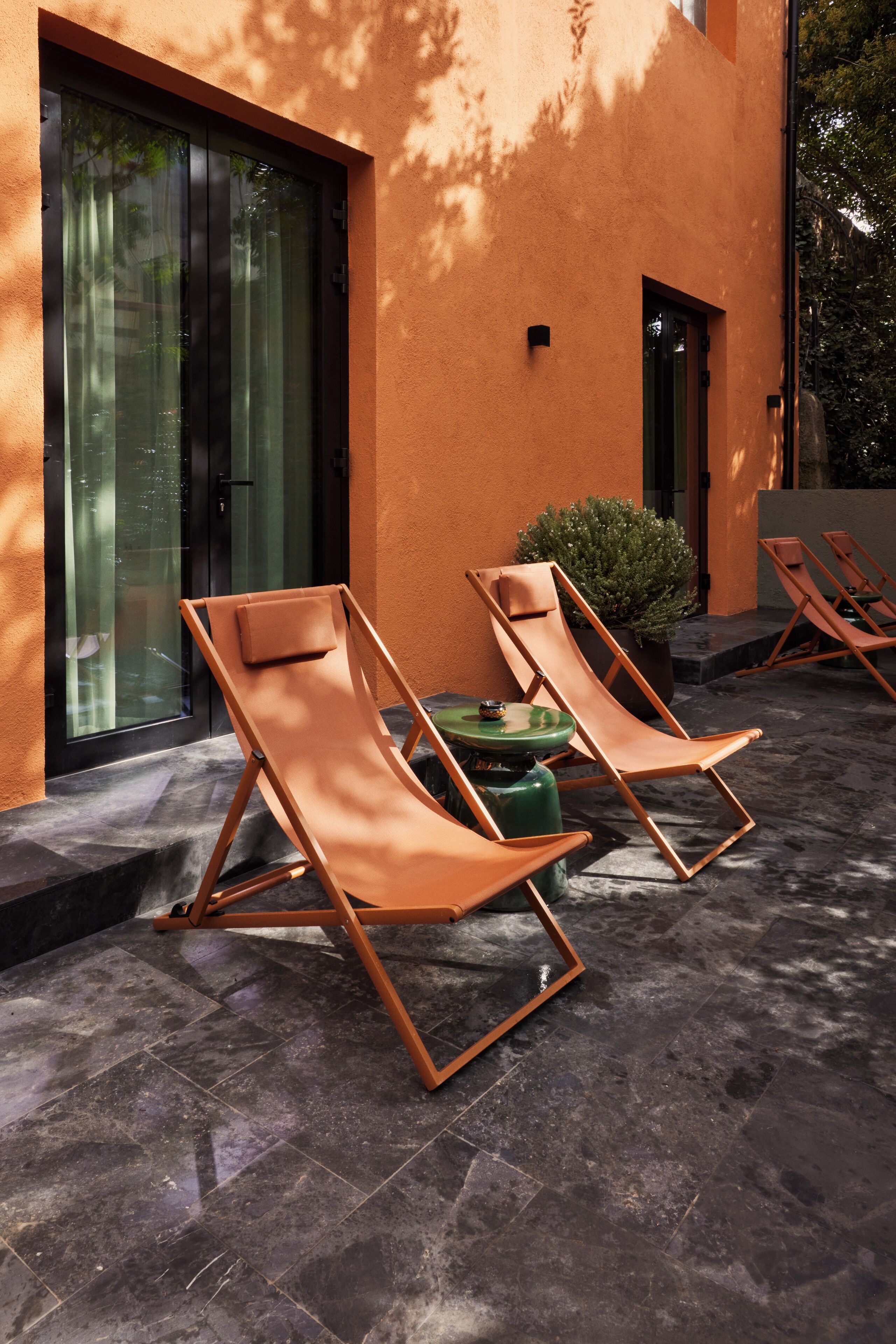 Un área de descanso al aire libre moderna con dos sillones, una mesita y una planta en maceta.