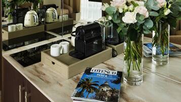 Un comptoir de cuisine d’hôtel avec une machine à café, une bouilloire et un magazine intitulé « COTESUD NICE ».