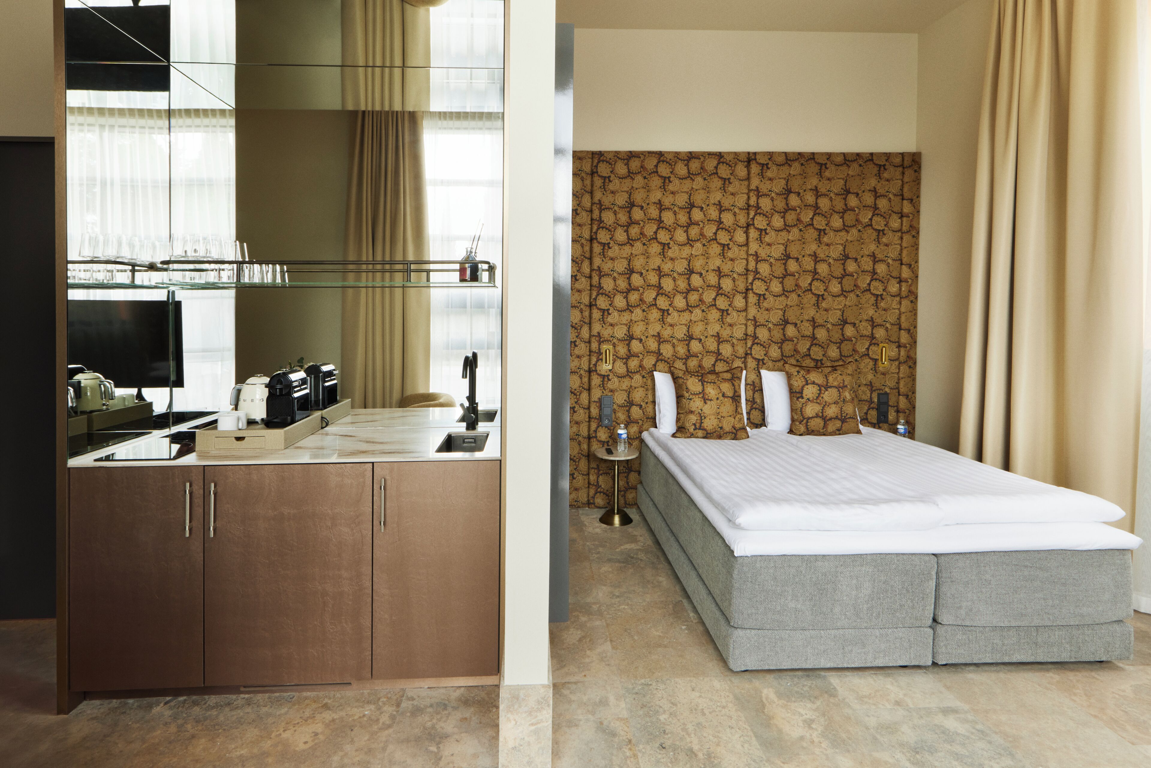 Ein Hotelzimmer mit einem Holzschrank, einem Bett mit grauer Bettwäsche und einer Wand mit Muster.
