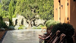 Un espace extérieur aménagé avec une surface pavée, des chaises longues et un mur en pierre.