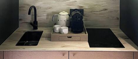 A modern kitchen with a built-in sink, a coffee maker, and a kettle on the countertop.