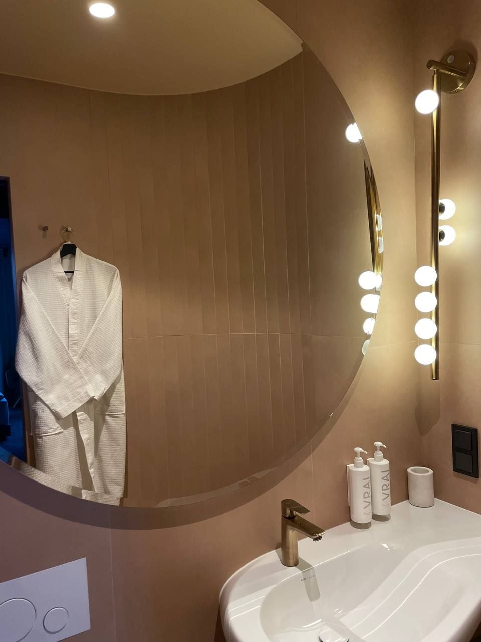 Un baño moderno con un espejo grande, tocador e iluminación.