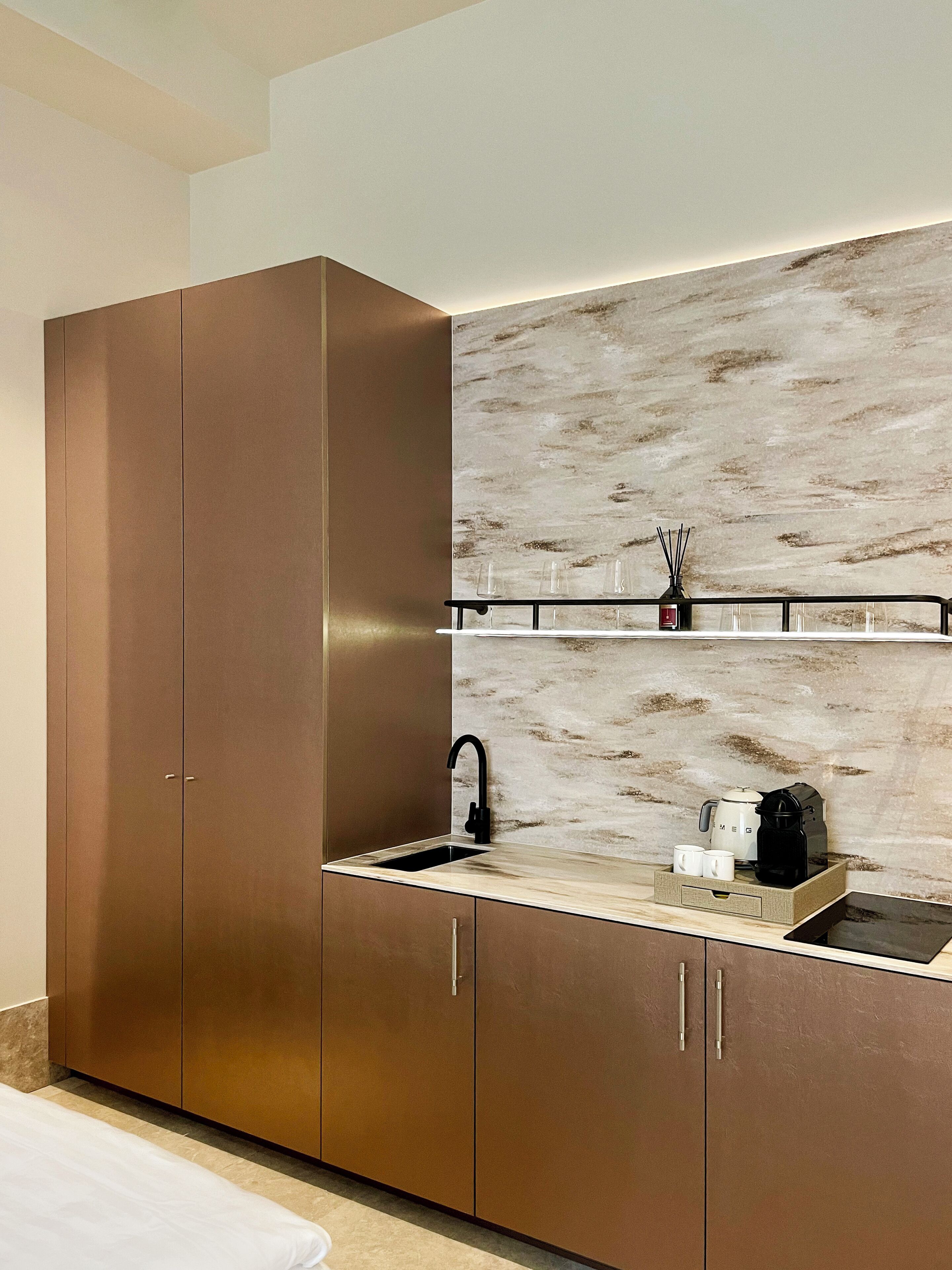 A modern kitchen with a built-in oven, a sink, and a countertop with a coffee maker and cups.