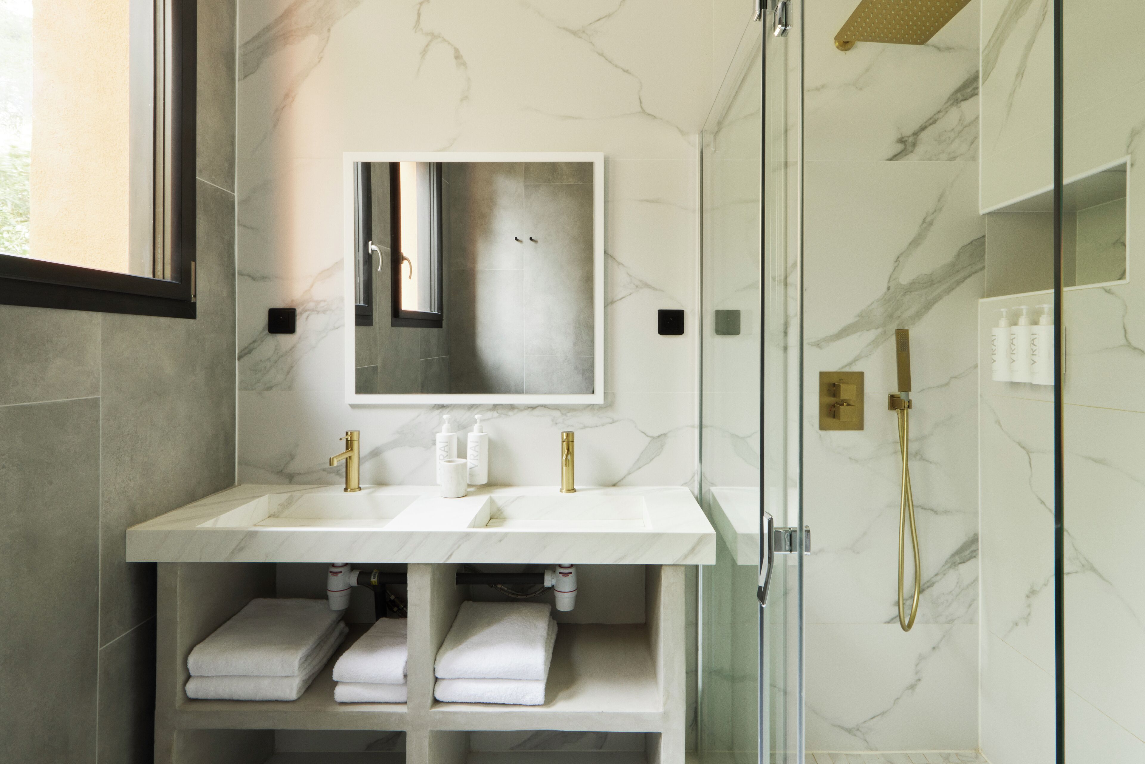 A bathroom with two sinks, a mirror, and a glass shower enclosure.