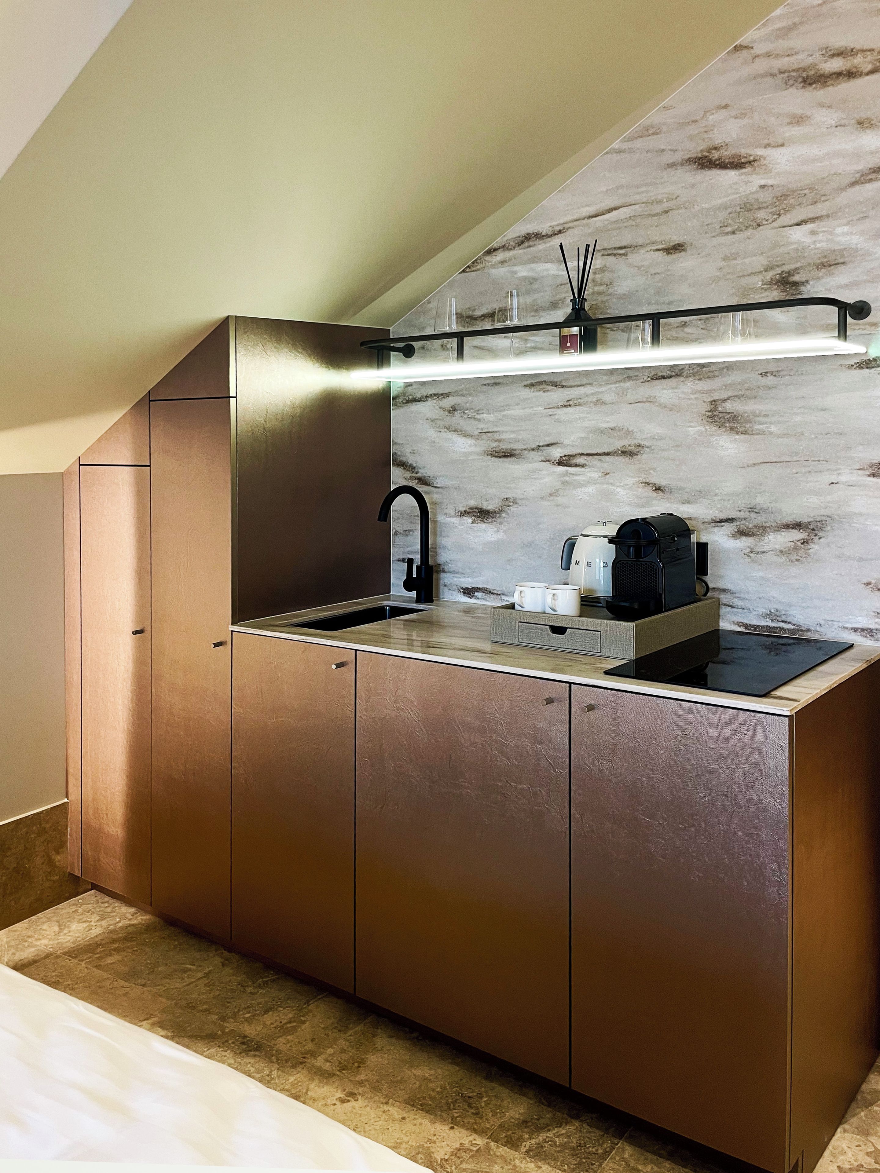 Cocina compacta con lavaplatos integrado, cafetera y encimera con repisa de vidrio arriba.