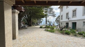 Une cour pavée de pierres, avec des piliers en pierre, des arbres et un bâtiment doté d’une porte verte.