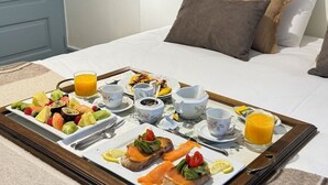 Un plateau de petit-déjeuner sur un lit, avec divers aliments, boissons et ustensiles.