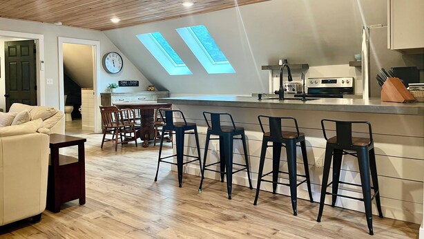A modern kitchen with a bar area, wooden ceiling, and skylights. - The Barnhouse with hot tub (New Gloucester)