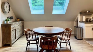 A kitchen with a round wooden table and four chairs, two skylights, a clock, and a sign that reads "Coffee & Friends". - The Barnhouse with hot tub (New Gloucester)