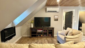 A living room with a TV, a sofa, and a wooden cabinet. - The Barnhouse with hot tub (New Gloucester)
