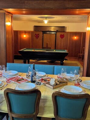 Enjoy a casual dining experience with a pool table in the background, surrounded by comfortable seating and a beautifully set table.
