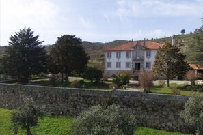 Situated on a hillside, this hotel features a large, white building with a red-tiled roof and a symmetrical facade.