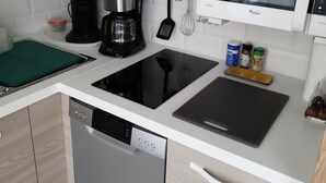 Una cuina moderna amb rentaplats, cafetera, forn de microones i tabla de tallar.