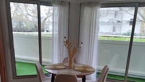 Una zona de menjador amb una taula rodona, quatre cadires i un ram d'flors seques.