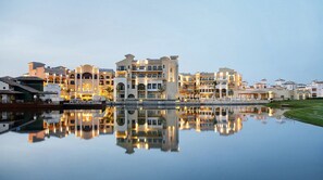 A waterfront hotel with multiple buildings, a reflecting pool, and a well-maintained lawn.