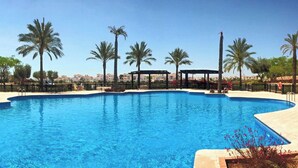 Una grande piscina cristallina con palme e un gazebo sullo sfondo.