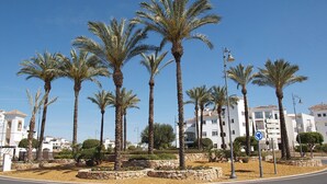 Una strada con palme, un muro in pietra e un edificio con un'insegna che indica un ristorante.