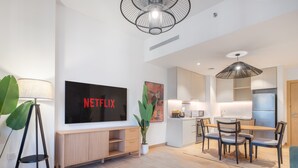 Un soggiorno moderno con una televisione a schermo piatto, un'area pranzo e una cucina.