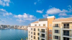 Una zona residenziale costiera con edifici moderni, un porto turistico con barche e un cielo azzurro limpido.