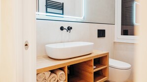 A modern bathroom with a white sink, wooden vanity, and a toilet.