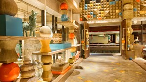 A modern interior with wooden shelves displaying various decorative items, a patterned floor, and a view into another room with a traditional setting. - Tijili Hotel Seminyak (Seminyak)