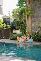 Uma piscina com espreguiçadeira e uma pessoa relaxando à beira da piscina.