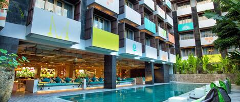A hotel with a swimming pool, outdoor seating, and a modern architectural design.