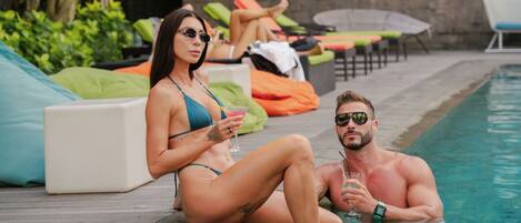 A swimming pool area with lounge chairs and a stone wall.