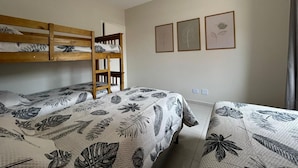 Une chambre avec des lits superposés, un ventilateur de plafond et des œuvres d’art encadrées accrochées au mur.