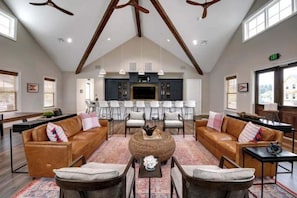 A spacious living area with a high ceiling, a central coffee table, sofas, and a dining area with chairs.
