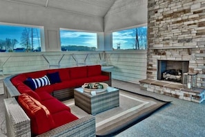 A modern living room with a red sectional sofa, a fireplace, and large windows.