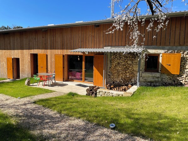 A wooden building with a stone wall, a covered patio, and a gravel path.