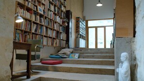 A library with bookshelves, a desk, a chair, and a statue.