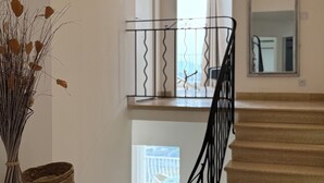 Eine Treppe mit schwarzer Geländer, einer Chandelüster und einer Pflanzvase mit Trockenpflanzen auf einer Theke.