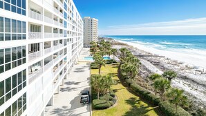 Een modern hotel met zwembad, uitzicht op het strand en een parkeerplaats.