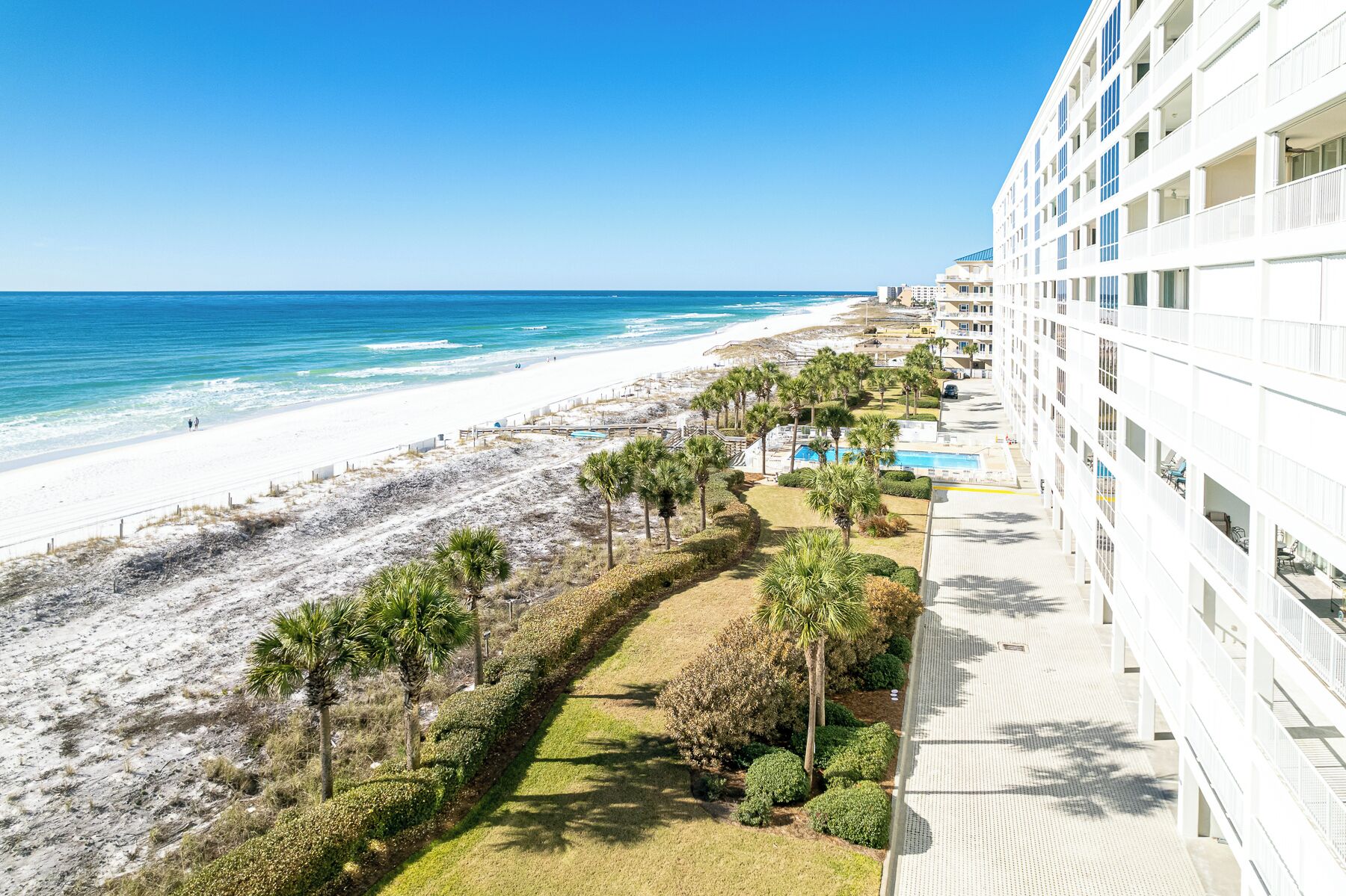 A beachfront hotel with a pool, beach access, and a view of the ocean.