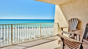 A balcony with a view of the beach, wooden chairs, and a railing. - Stunning BH 301A w/Seasonal Beach Service (Miramar Beach)