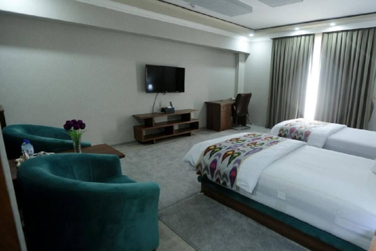 A hotel room with two beds, a TV, a desk, and a chair.