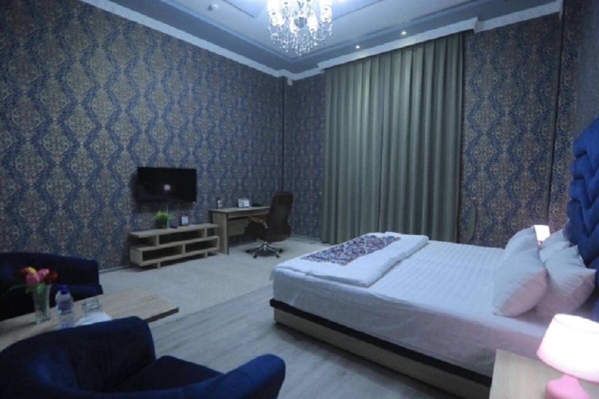 A hotel room with a bed, a desk, a chair, a TV, and a sofa.