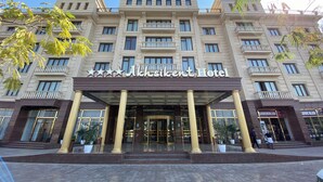 Een hotel met meerdere verdiepingen in klassieke bouwstijl, met een opvallende ingang met een luifel die wordt gedragen door kolommen.