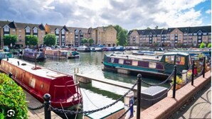 A canal with narrowboats docked along the water's edge, surrounded by terraced buildings. - The Coniston Rooms (Kings Langley)