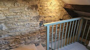 Un muro in pietra con una trave di legno e una ringhiera bianca.