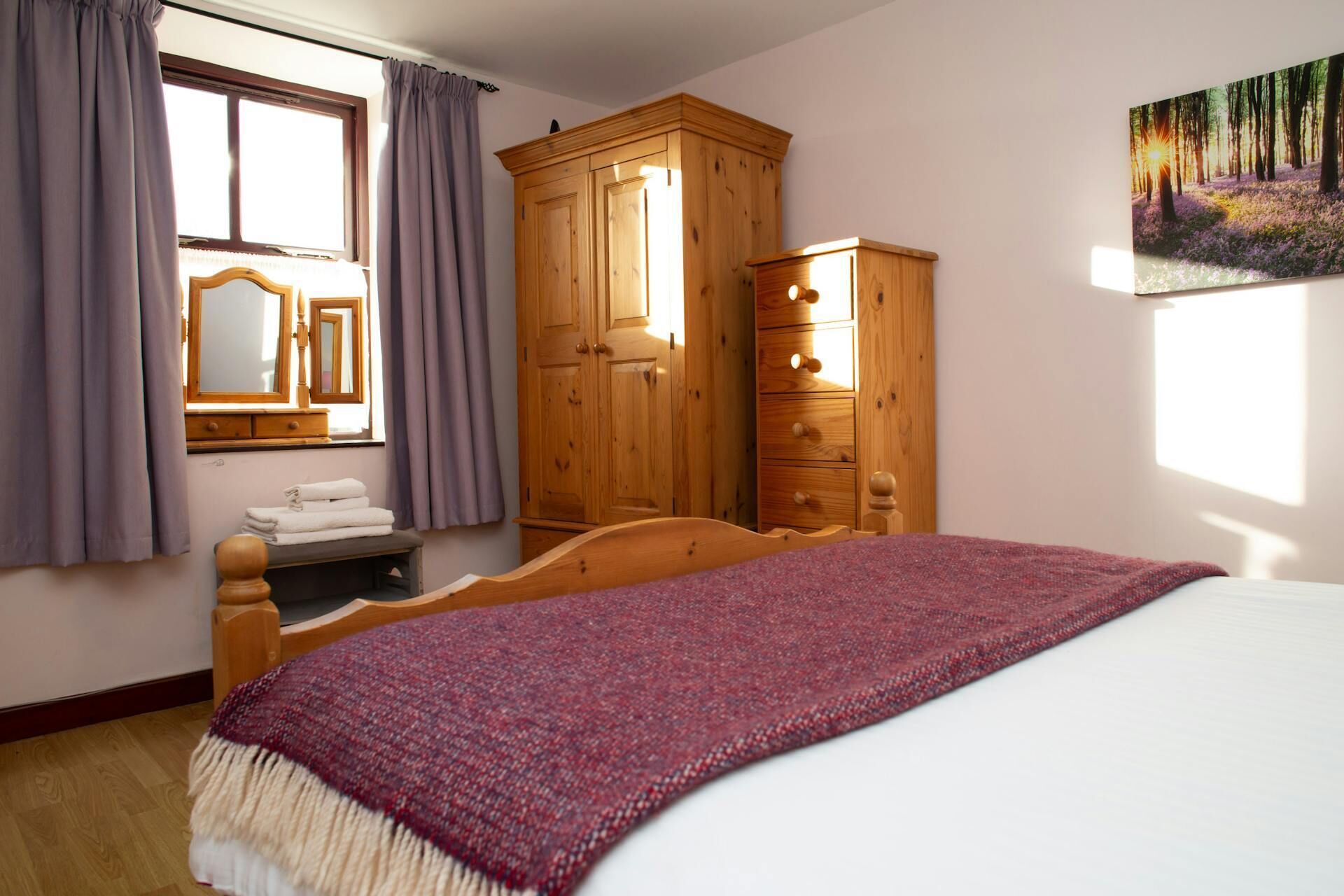 Un dormitorio con cama, armario de madera y un cuadro en la pared.