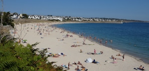 A beach with people sunbathing and swimming, a lighthouse in the distance, and houses along the coastline. - Vacation home, large garden, quiet location, near Pointe du Raz and Audierne (GOULIEN)