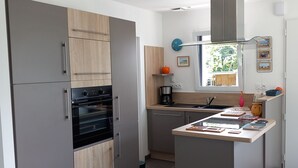 Une cuisine moderne avec des meubles gris, un four encastré et un îlot central doté d’un évier.