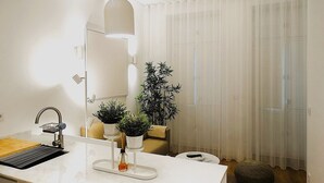 A modern kitchen with a white countertop, a sink, a hanging light, and a potted plant. - CA.Tanoeiros 1 (Funchal)