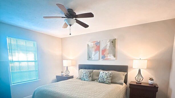 A bedroom with a bed, two bedside tables, a ceiling fan, and artwork on the wall. - Federal Ct- Charming 3-bedroom near Ag Center and MTSU in Murfreesboro (Murfreesboro)