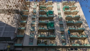 Ein mehrstöckiges Gebäude mit Balkonen, Geschäften und blauem Himmel.