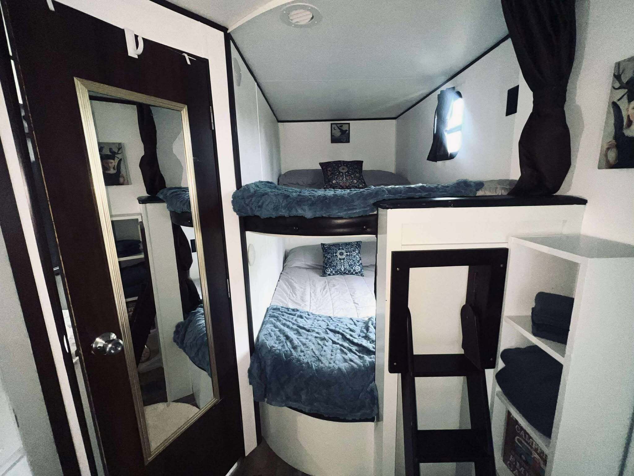 A compact room with a bunk bed, a small desk, and a wardrobe.