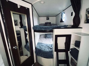 A compact room with a bunk bed, a small desk, and a wardrobe.